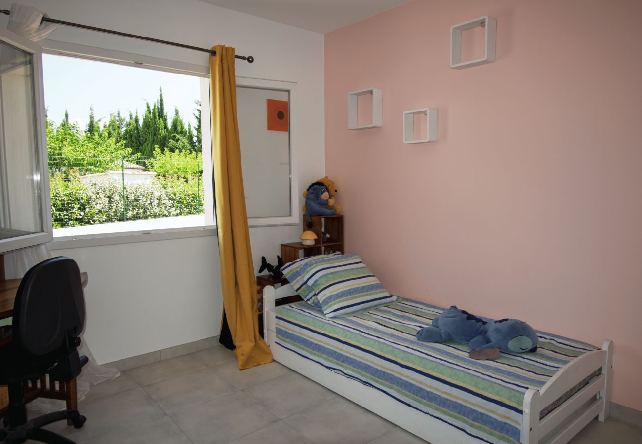 Kinderzimmer mit Einzelbett, rosa Wand und Gartenblick.