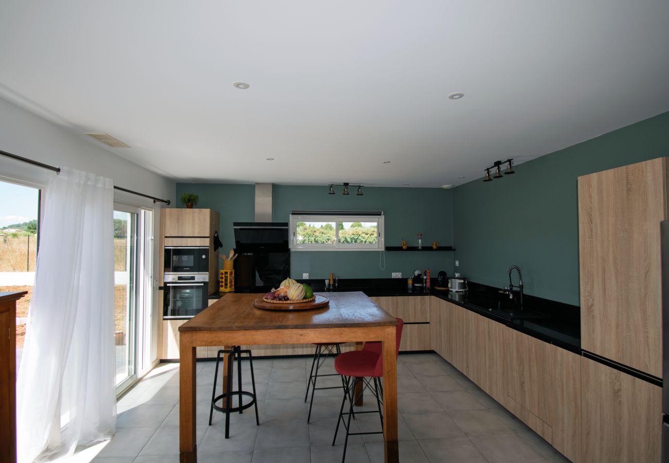 Modern equipped kitchen with wooden island and bright window.