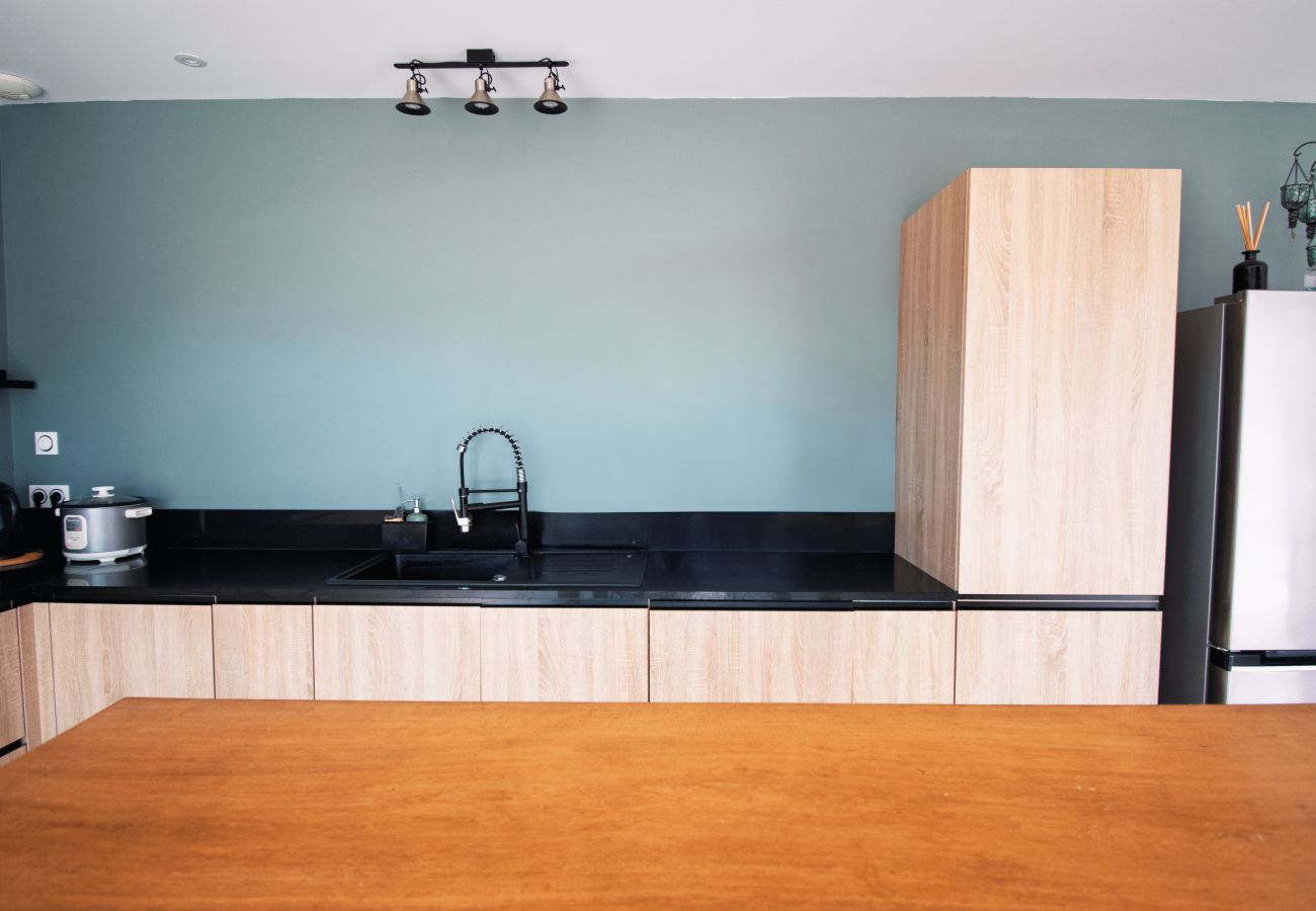 Modern equipped kitchen with sink, wood cabinets and black top.