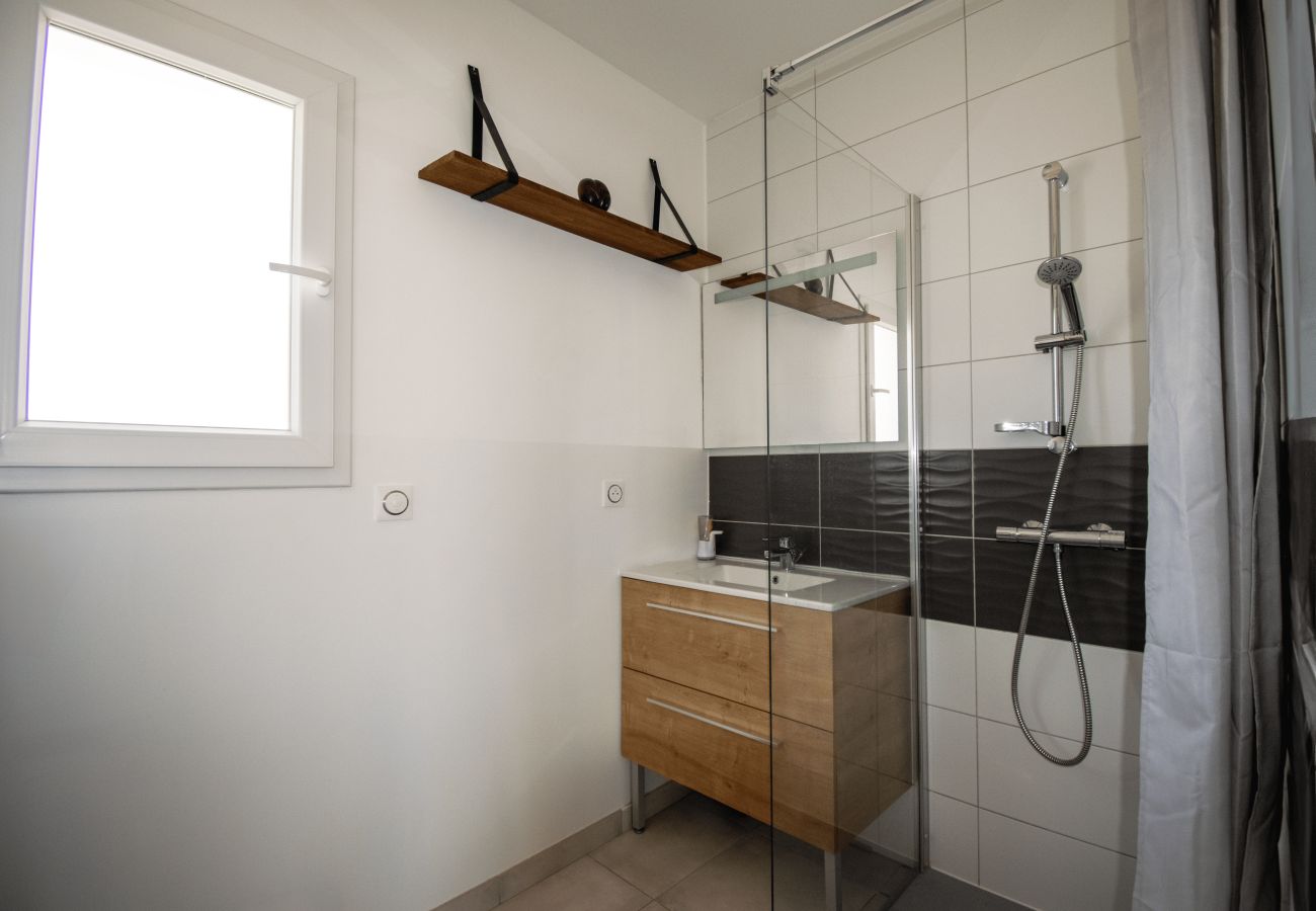 Bathroom with walk-in shower, wooden cabinet and simple design.