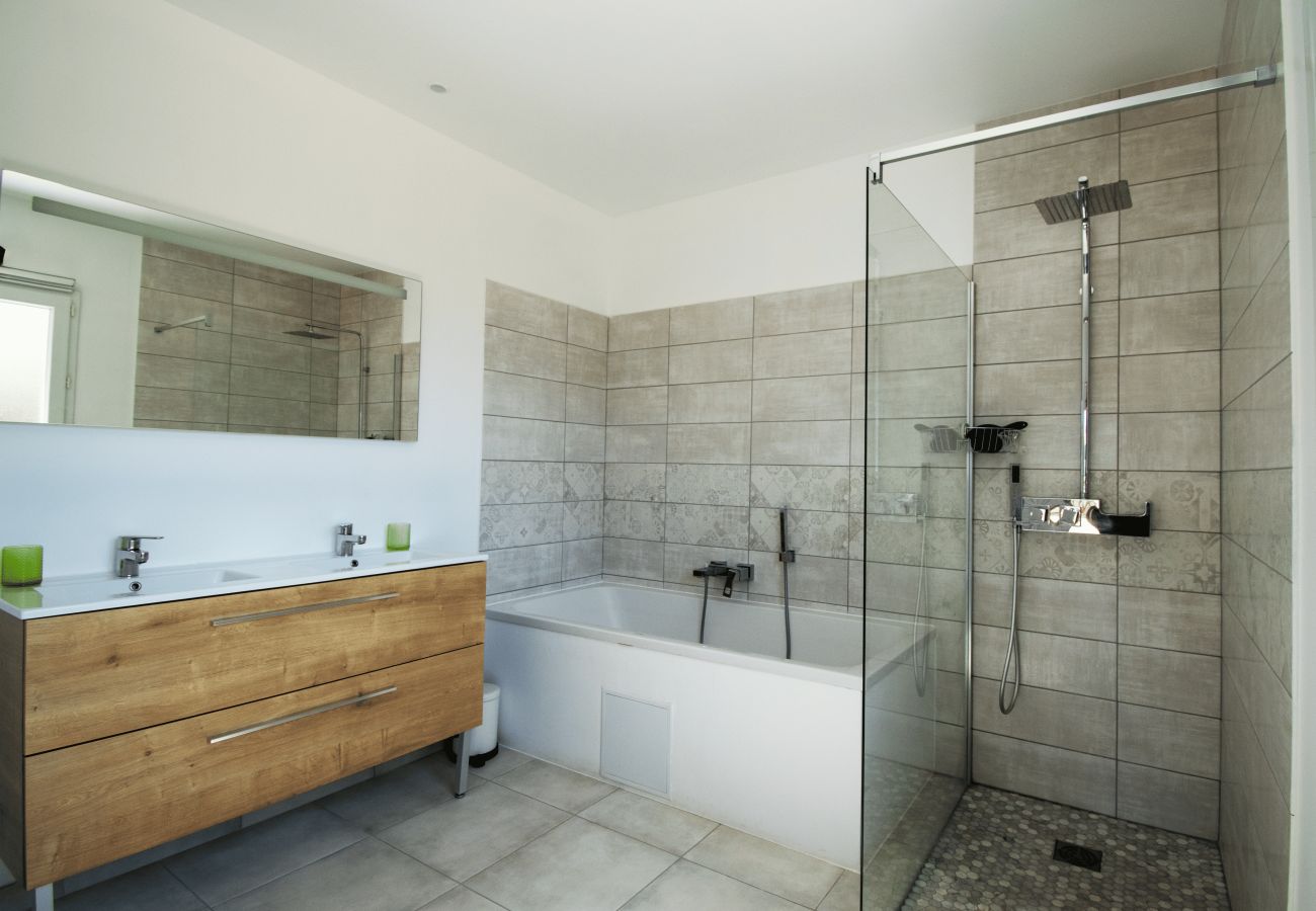 Bathroom with walk-in shower, bathtub and wooden cabinet.