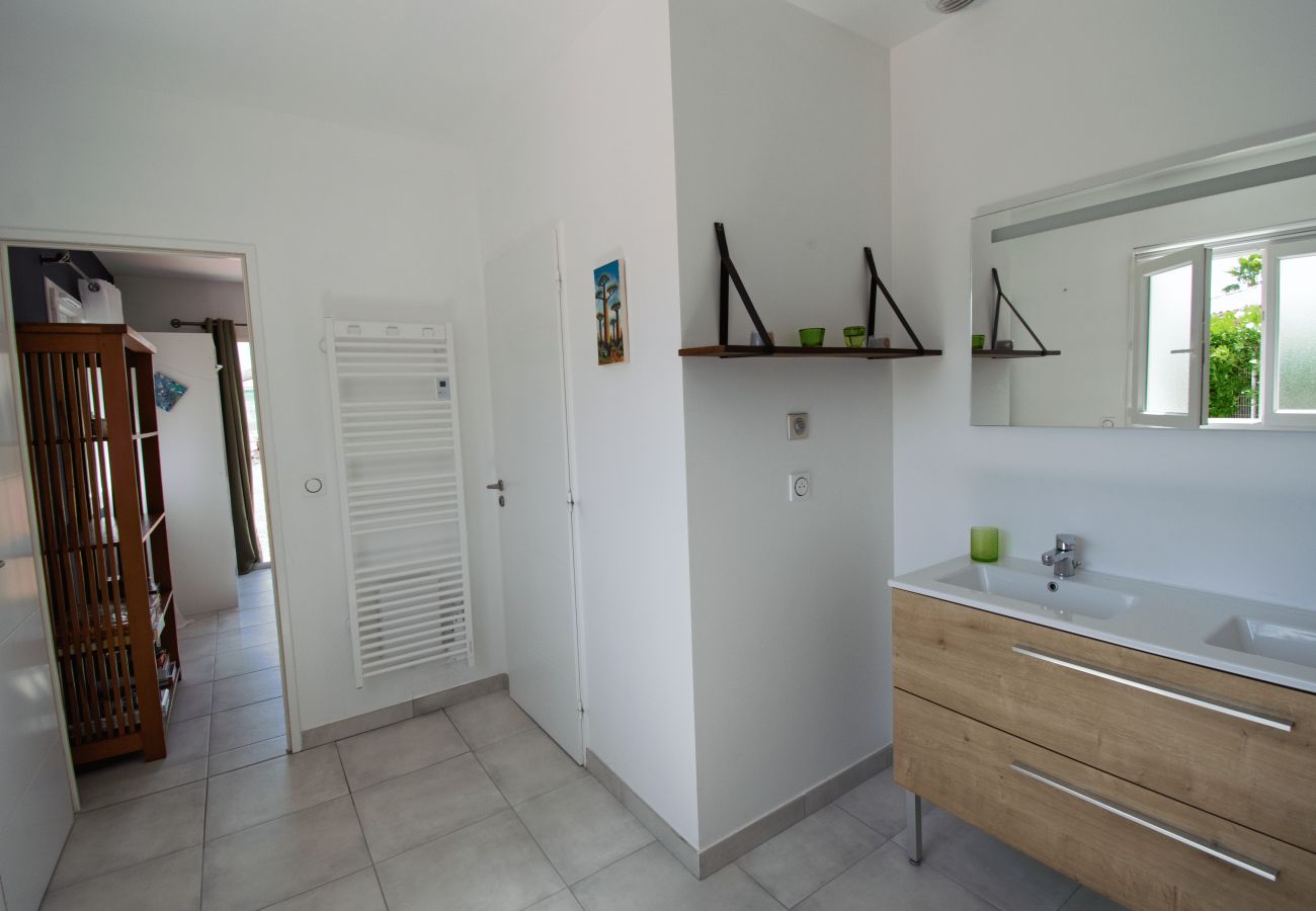 Double sink bathroom with wooden cabinet and bright mirror.