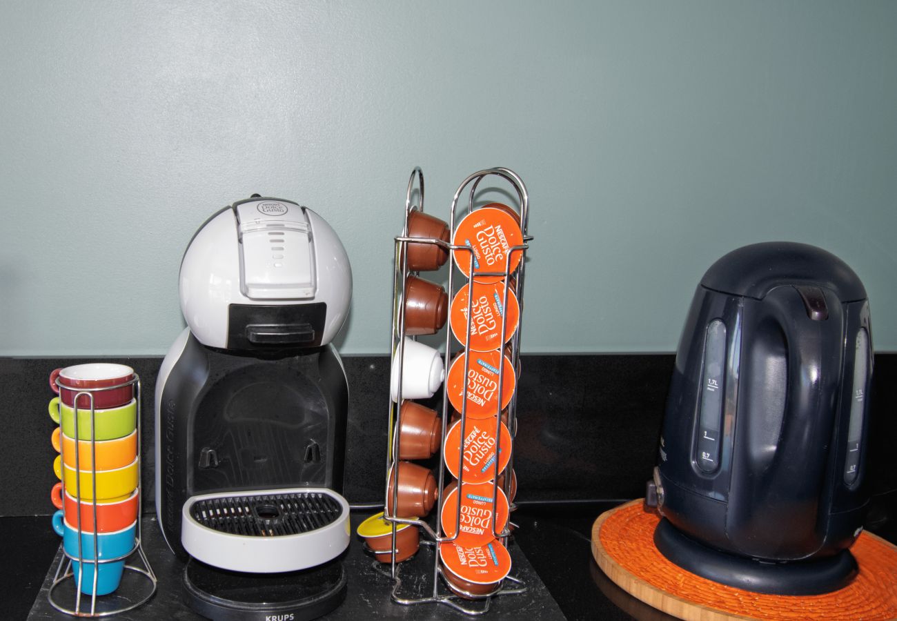 Rincón de café con cafetera de cápsulas y hervidor eléctrico.