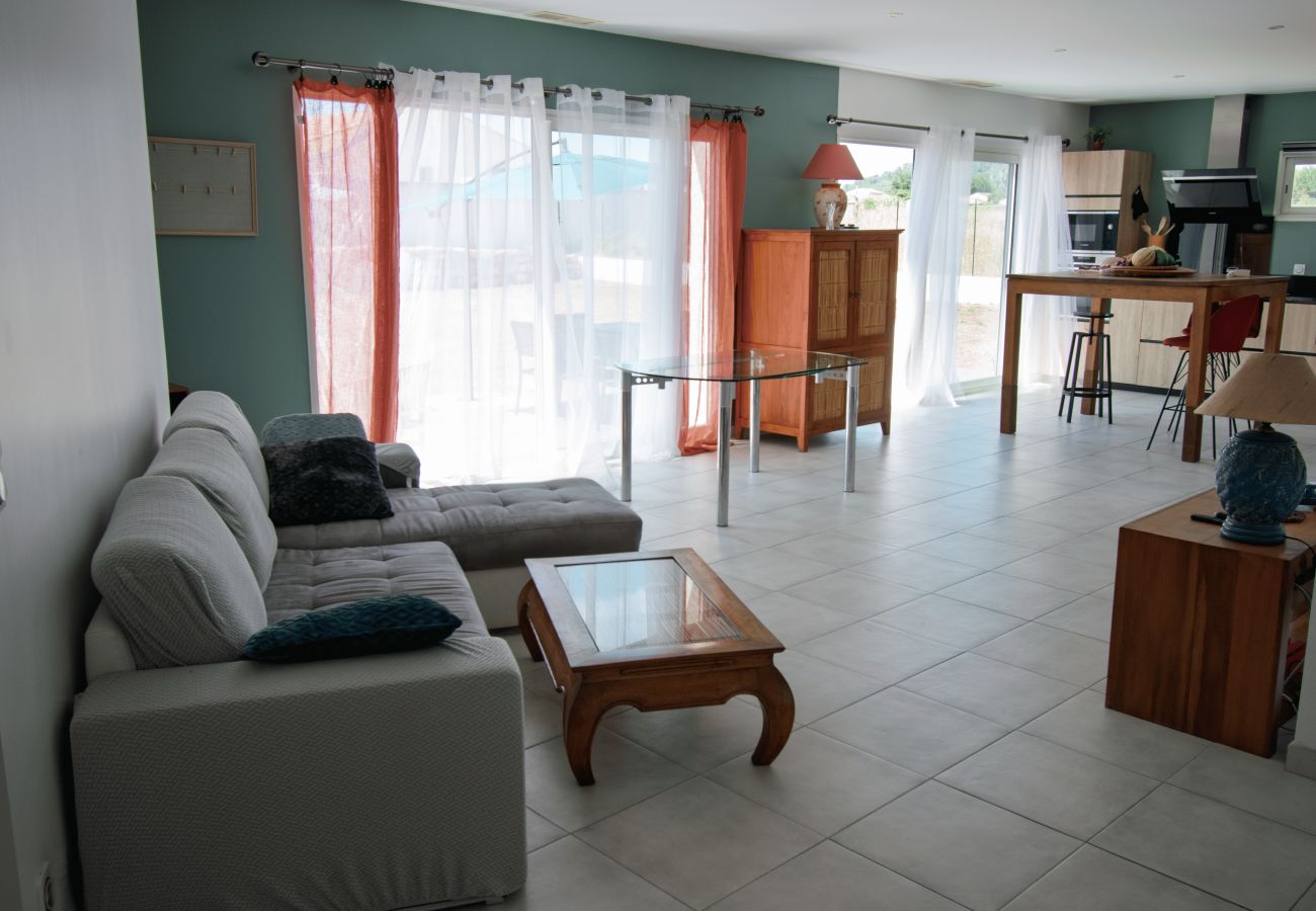 Salón moderno y luminoso con sofá y ventanales hacia la terraza.