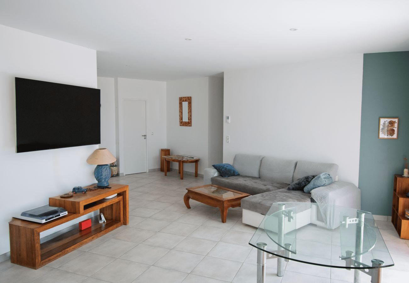 Salón luminoso con sofá esquinero, TV de pantalla plana y muebles de madera.