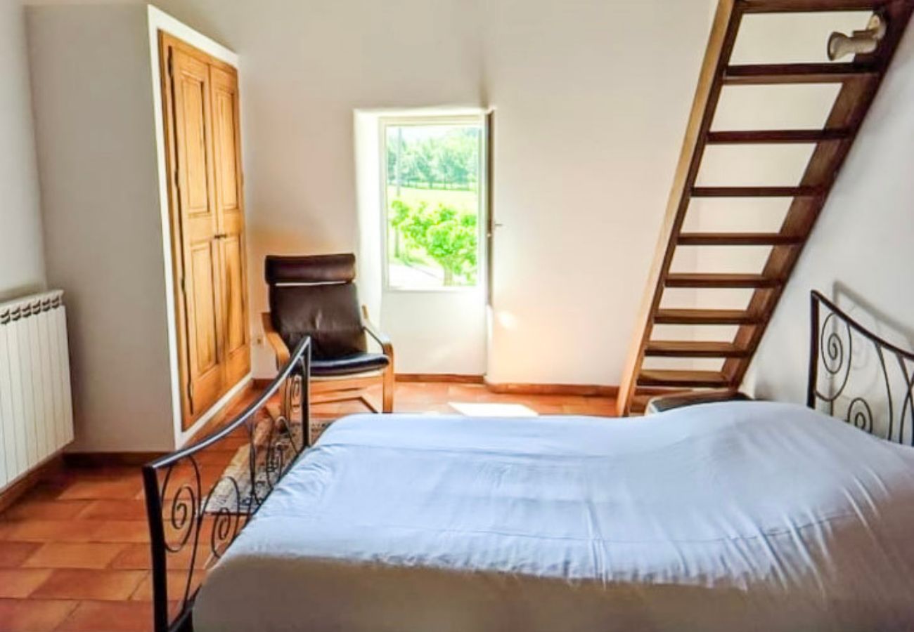 chambre avec lit double, fauteuil et accès mezzanine en bois
