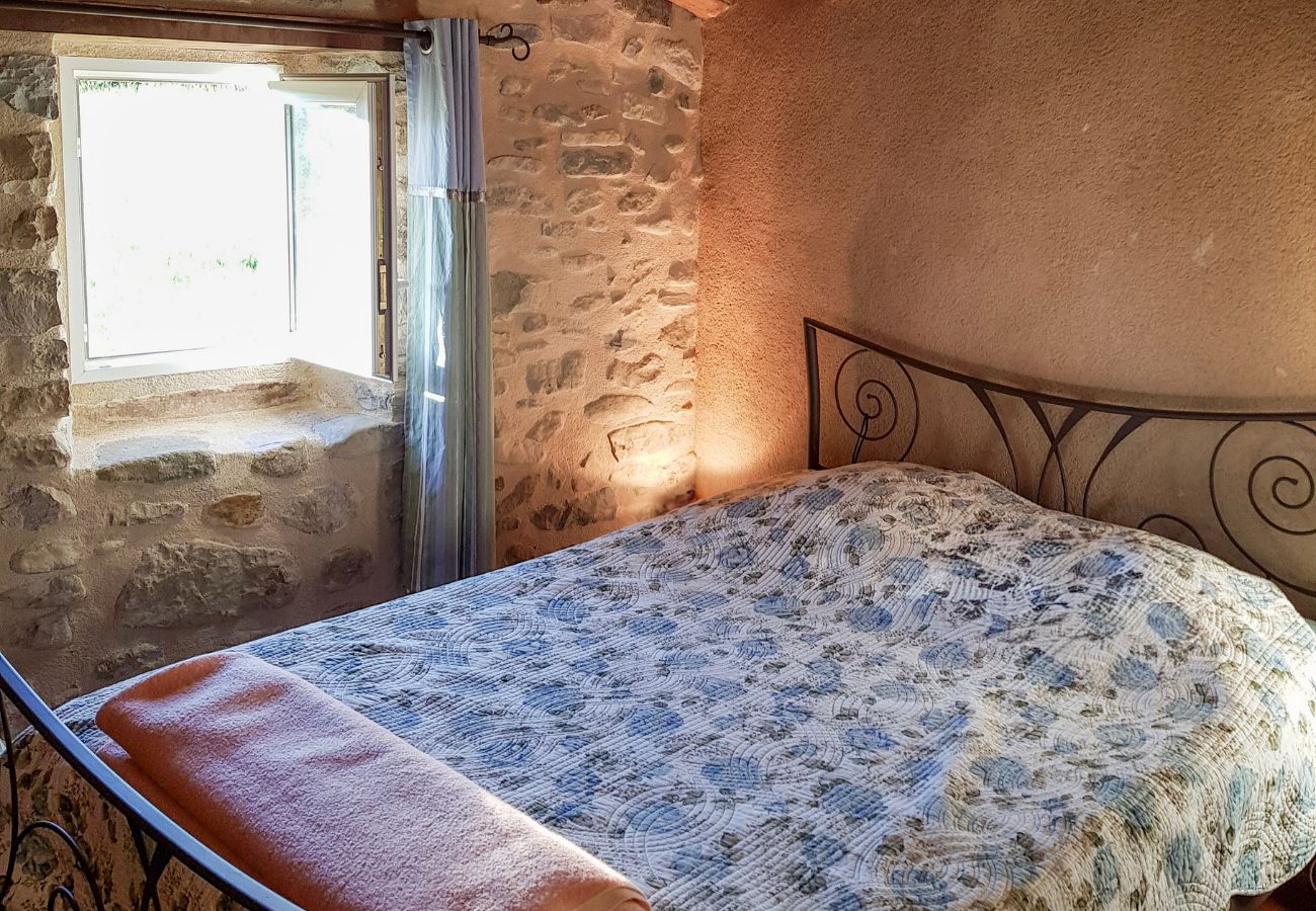 chambre lumineuse avec lit double et mur en pierre apparente